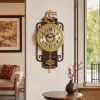 A golden deer-shaped decorative wall clock with a redwood base, a round shell-patterned dial, and Chinese "Fu" character tassels details Picture